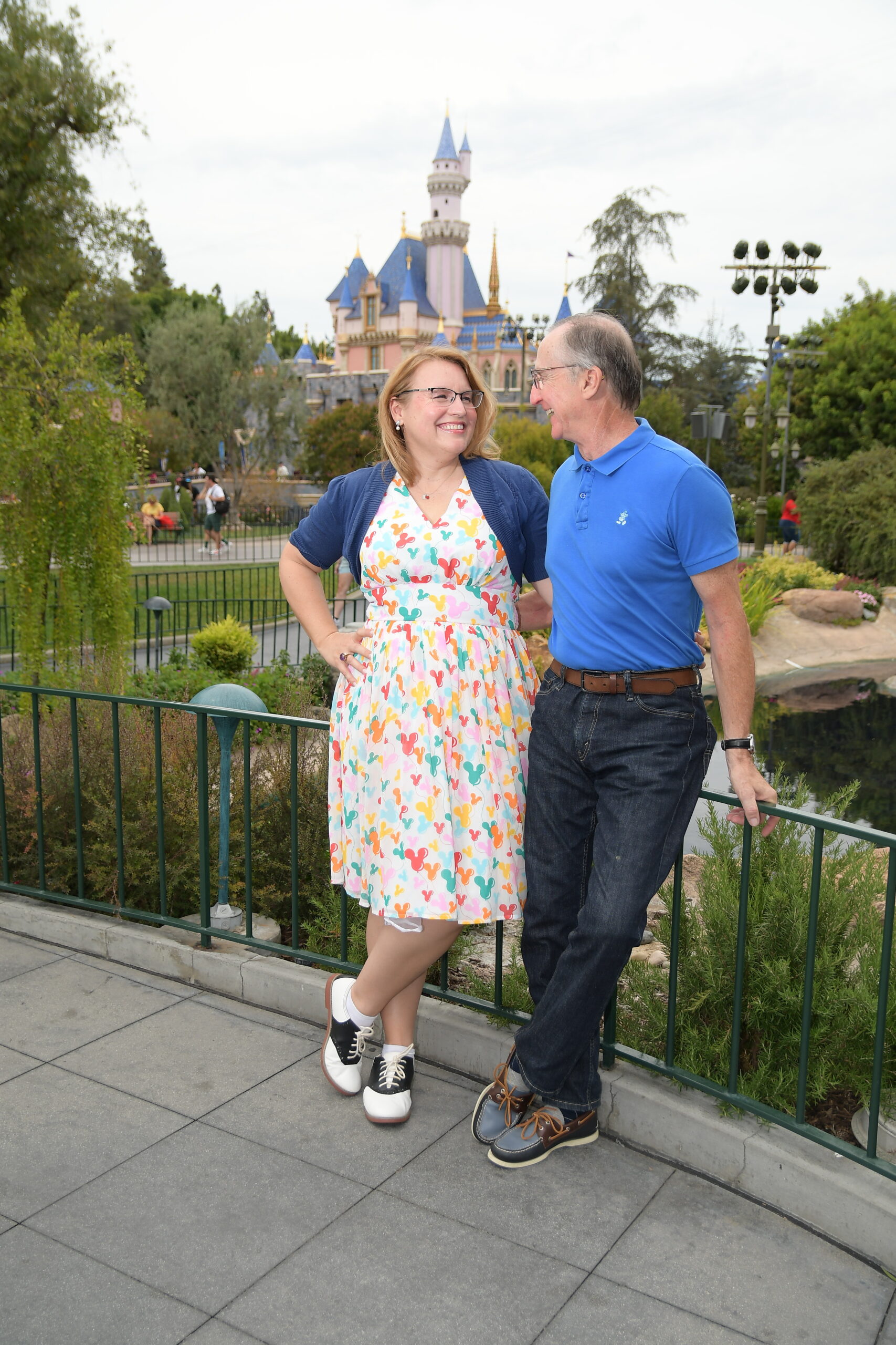 Jennifer and Joe Davis, owners of Sweetbay Travel Concierge, standing together in front of Sleeping Beauty Castle at Disneyland